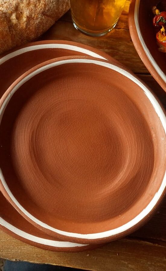 Red clay steak plate in service with grilled dishes